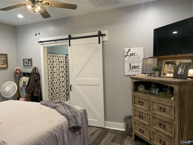 bedroom featuring a barn door, dark wood-type flooring, and ceiling fan