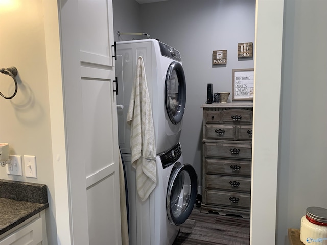 laundry room featuring stacked washer and dryer and cabinets