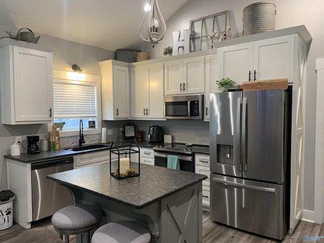 kitchen featuring a kitchen bar, sink, a kitchen island, stainless steel appliances, and white cabinets