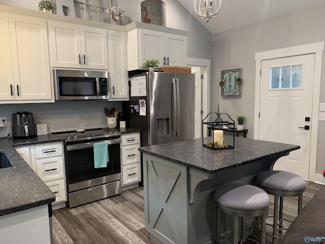 kitchen with white cabinetry, appliances with stainless steel finishes, a center island, and hanging light fixtures