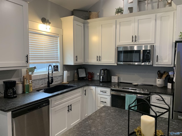 kitchen featuring white cabinetry, sink, stainless steel appliances, and dark stone countertops