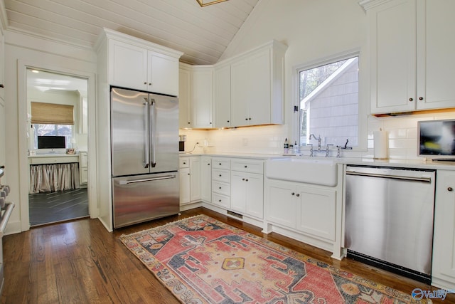 kitchen with lofted ceiling, sink, stainless steel appliances, dark hardwood / wood-style floors, and white cabinets