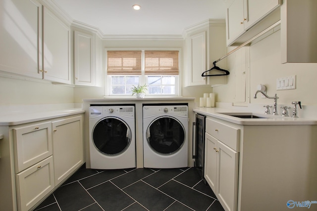 laundry area with sink, crown molding, cabinets, dark tile patterned floors, and washing machine and dryer