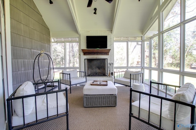 sunroom / solarium featuring ceiling fan, lofted ceiling with beams, and a brick fireplace