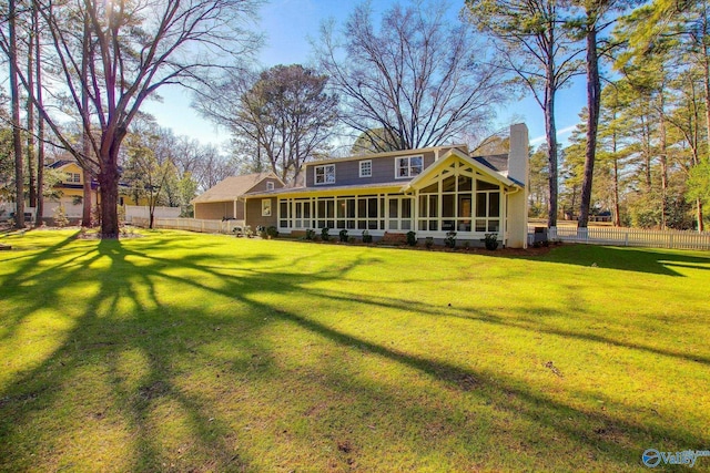 rear view of house with a yard and a sunroom