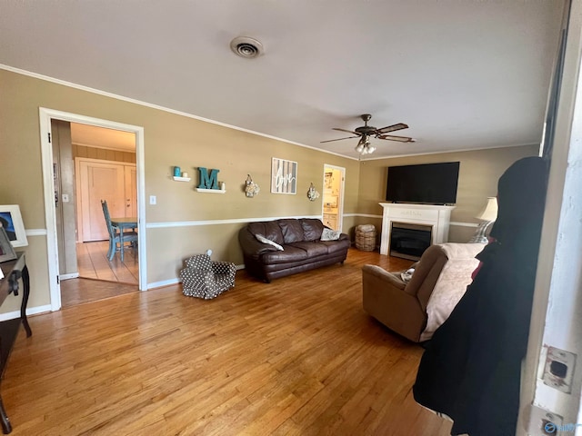 living room with hardwood / wood-style floors, ceiling fan, and crown molding