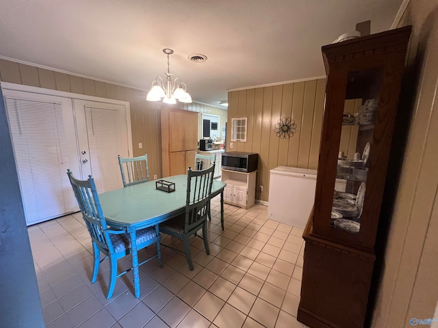 tiled dining area with wooden walls, crown molding, and a notable chandelier