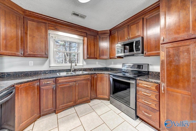 kitchen with dark stone countertops, light tile patterned floors, sink, and appliances with stainless steel finishes