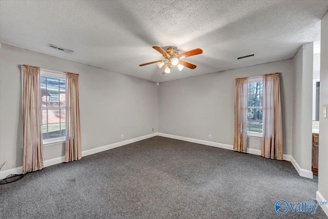 unfurnished room with dark colored carpet, ceiling fan, a textured ceiling, and a wealth of natural light