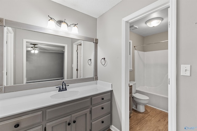 full bathroom with bathing tub / shower combination, ceiling fan, hardwood / wood-style floors, vanity, and toilet