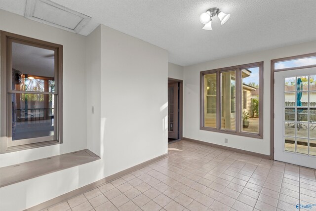 spare room with a textured ceiling and light tile patterned floors