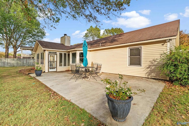 rear view of house featuring a lawn and a patio