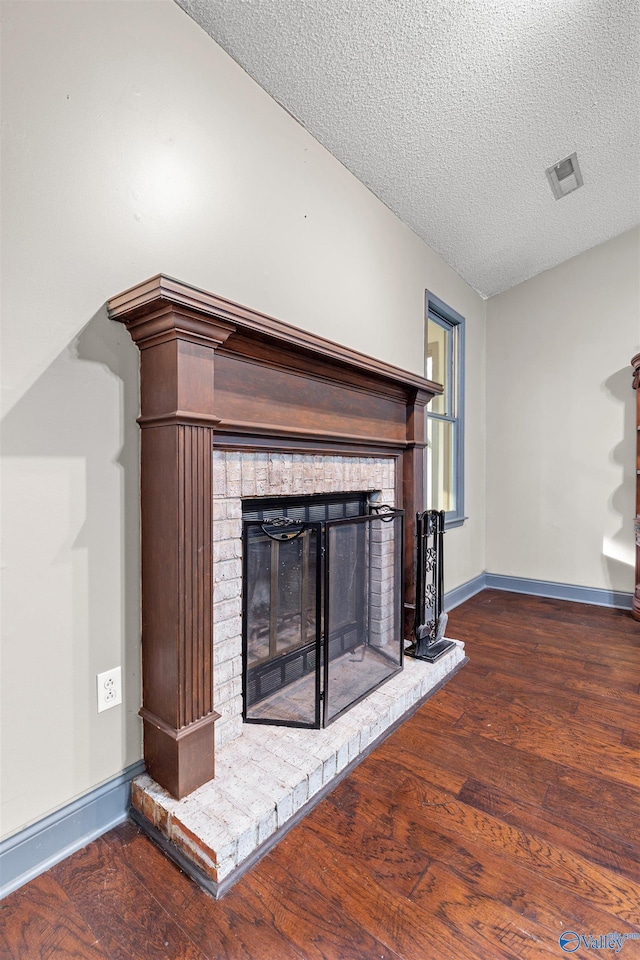 unfurnished living room featuring a fireplace, dark wood-type flooring, and a textured ceiling