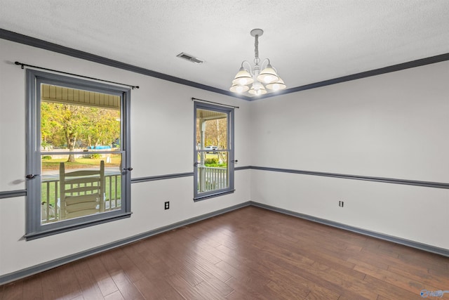 spare room with a chandelier, a healthy amount of sunlight, and a textured ceiling