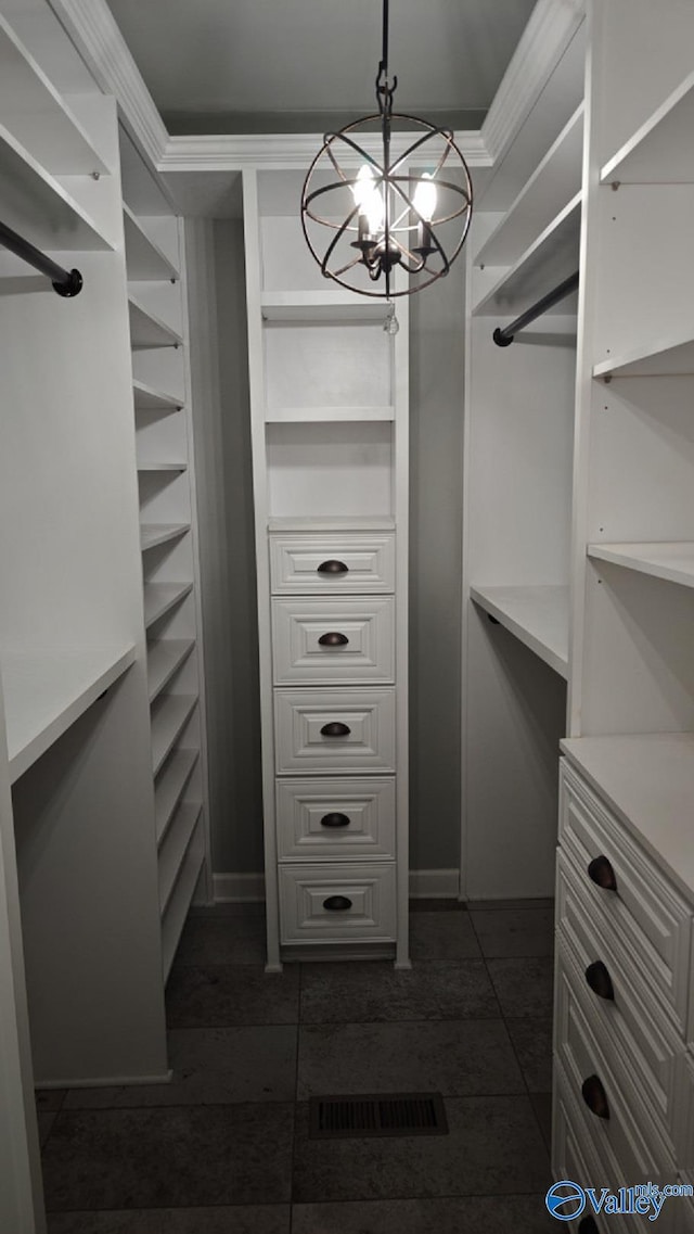 spacious closet featuring a chandelier and dark tile patterned floors