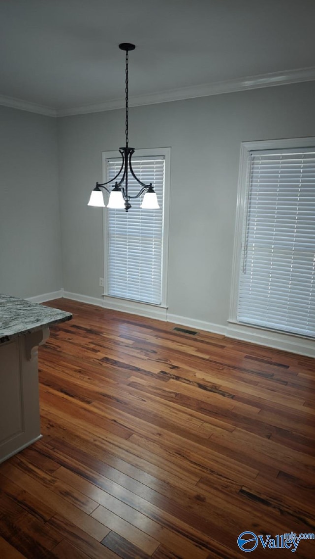 unfurnished dining area with ornamental molding, dark hardwood / wood-style floors, and a notable chandelier