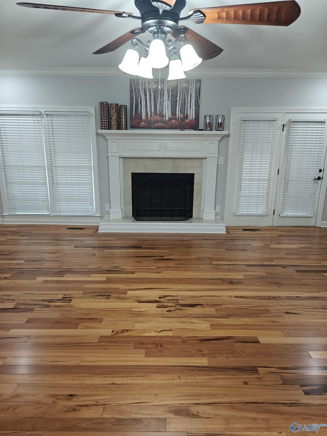 unfurnished living room with crown molding, ceiling fan, hardwood / wood-style floors, and a tile fireplace