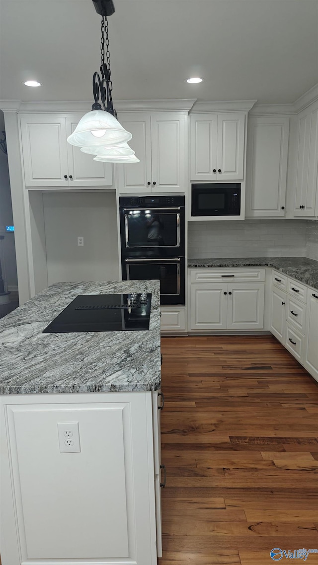 kitchen with pendant lighting, white cabinetry, light stone counters, black appliances, and dark hardwood / wood-style flooring