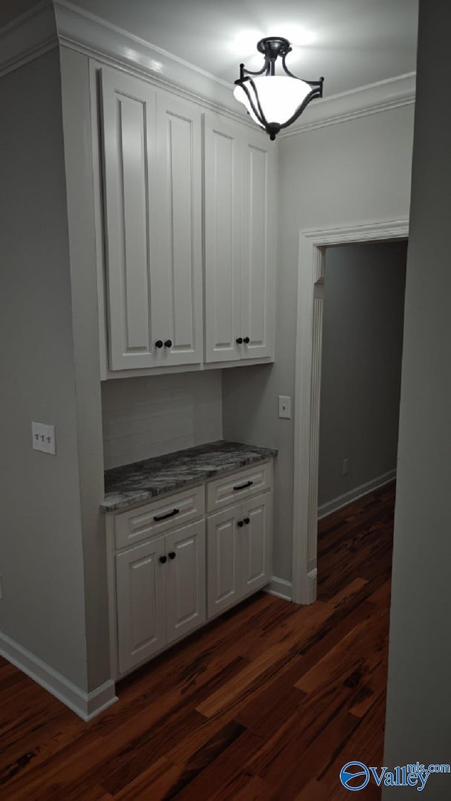 bar featuring white cabinetry, crown molding, and dark wood-type flooring