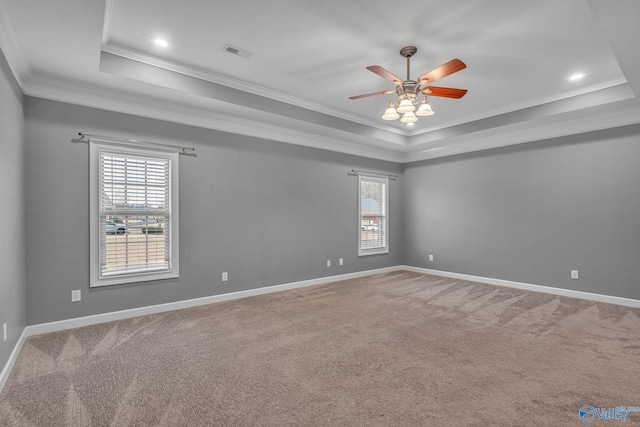 empty room featuring a tray ceiling, crown molding, and carpet flooring