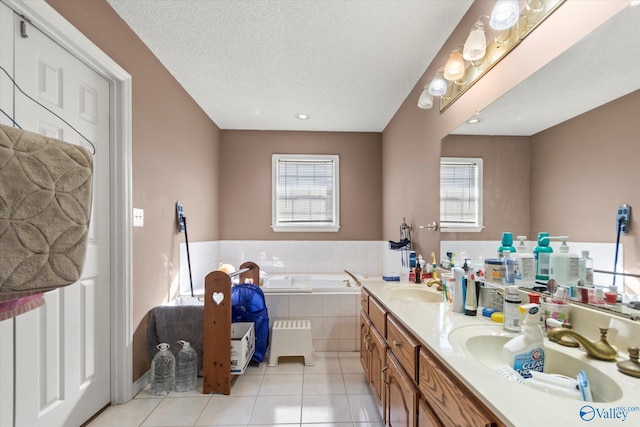 bathroom featuring vanity, tiled bath, tile patterned flooring, and a textured ceiling