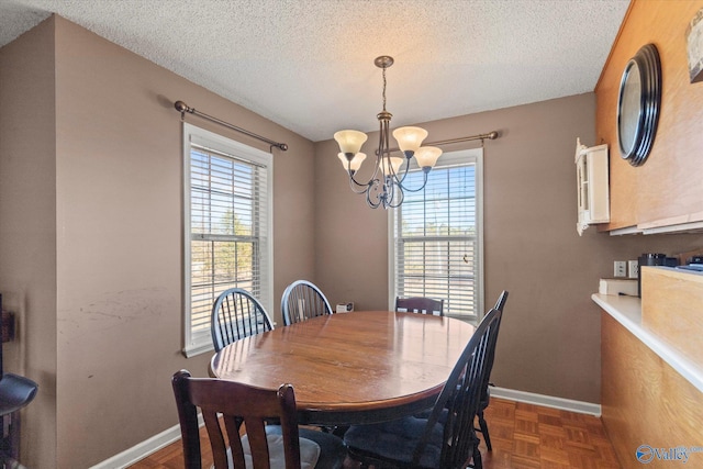 dining area with a notable chandelier, dark parquet flooring, and a textured ceiling