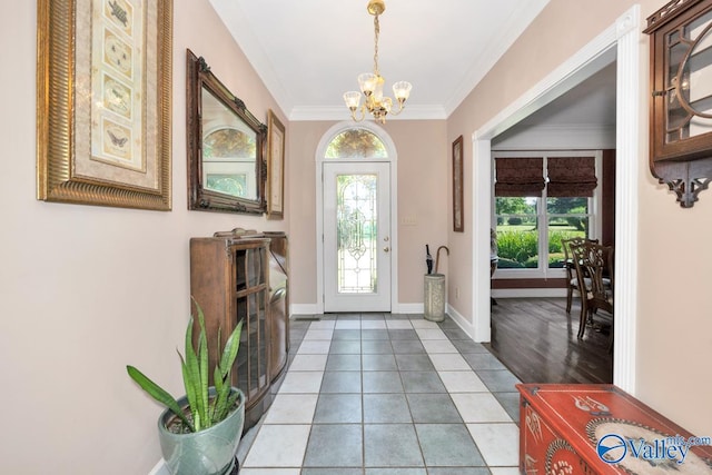 foyer with a notable chandelier, a wealth of natural light, light tile patterned flooring, and ornamental molding