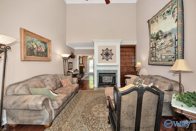 living room with ornamental molding, a tiled fireplace, ceiling fan, and hardwood / wood-style flooring