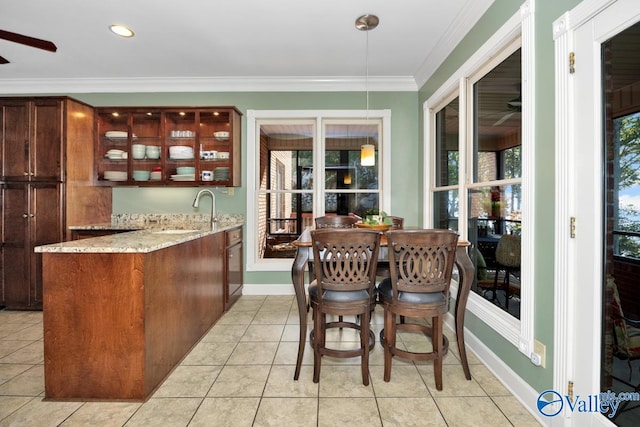 bar with sink, light tile patterned floors, crown molding, light stone countertops, and ceiling fan