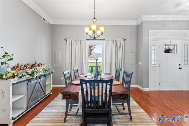 dining room with hardwood / wood-style flooring, an inviting chandelier, and crown molding