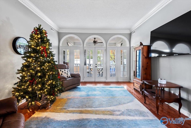 living room with french doors, a textured ceiling, hardwood / wood-style flooring, and crown molding