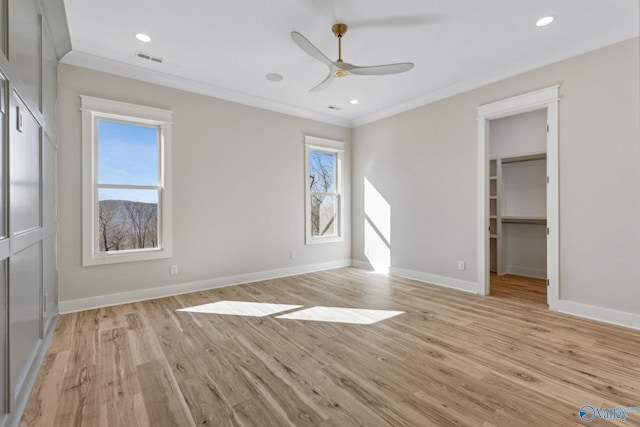 interior space with ceiling fan, a walk in closet, ornamental molding, and light hardwood / wood-style floors