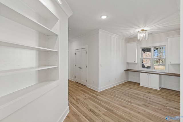 interior space with white cabinetry, built in desk, crown molding, and light hardwood / wood-style flooring