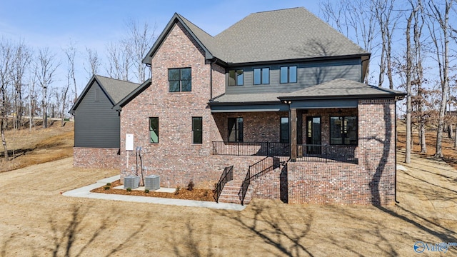 view of front of home featuring central AC unit, covered porch, and a front yard