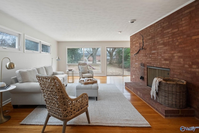 living room with light wood-style floors, a brick fireplace, and a textured ceiling