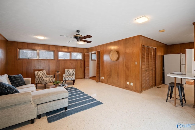 living room with ceiling fan and wooden walls