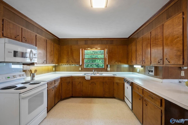 kitchen featuring brown cabinets, light floors, light countertops, a sink, and white appliances