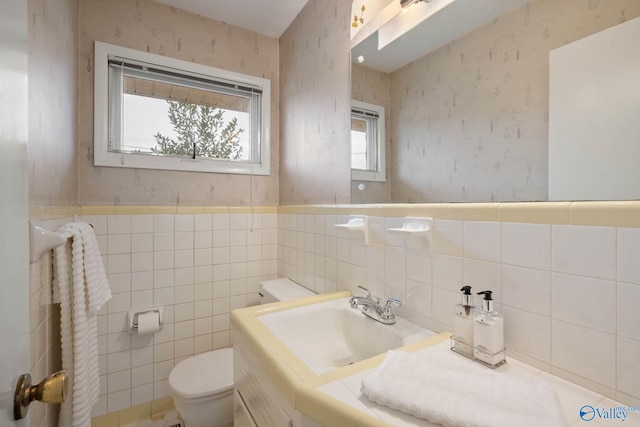 bathroom with toilet, wallpapered walls, a wainscoted wall, and vanity