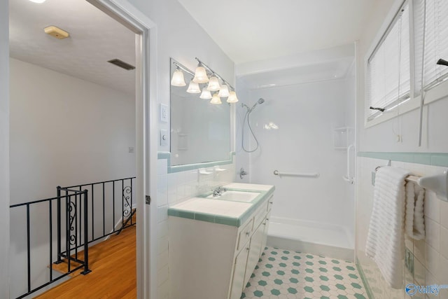 full bathroom with visible vents, a shower, wood finished floors, and vanity