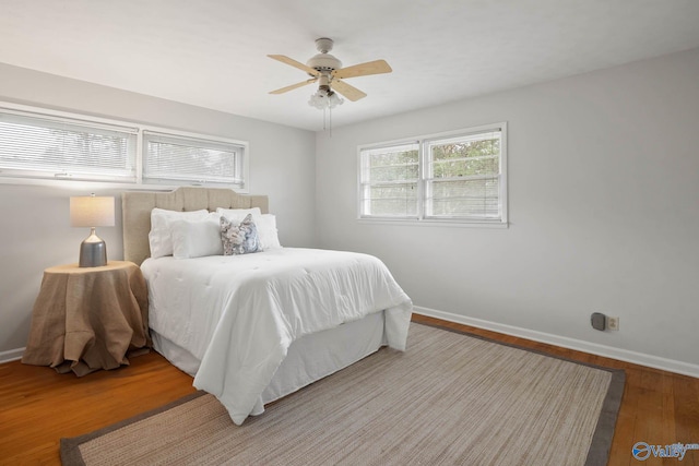 bedroom with ceiling fan, baseboards, and wood finished floors