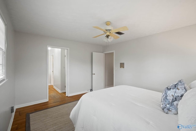 bedroom featuring ceiling fan, wood finished floors, visible vents, and baseboards