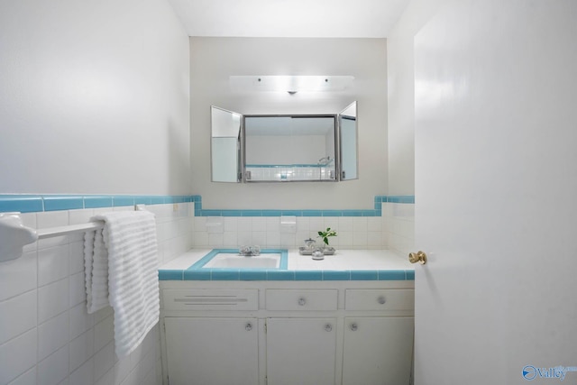 bathroom featuring tile walls, a wainscoted wall, and vanity