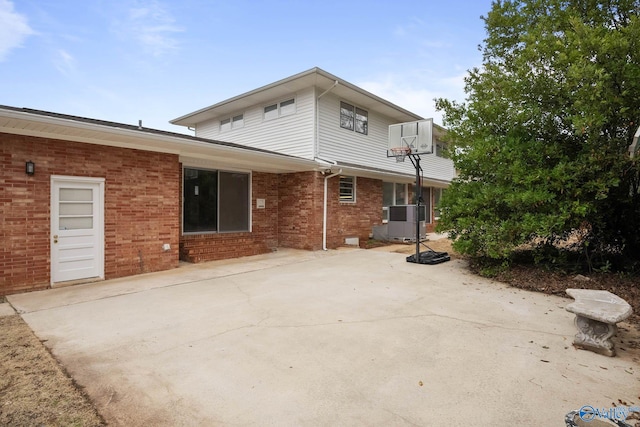 rear view of property with central AC, brick siding, and a patio area