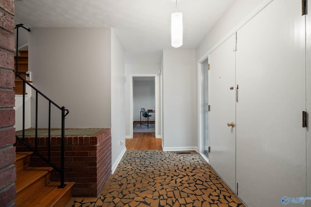 hall featuring stairway and baseboards