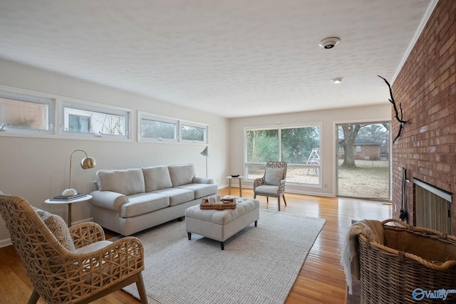 living area featuring baseboards, light wood-type flooring, and a brick fireplace