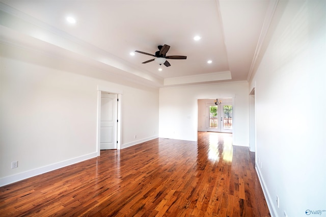 empty room with crown molding, ceiling fan, dark hardwood / wood-style floors, french doors, and a raised ceiling