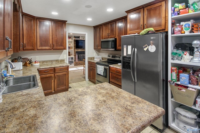 kitchen featuring sink, kitchen peninsula, stainless steel appliances, and light tile patterned floors