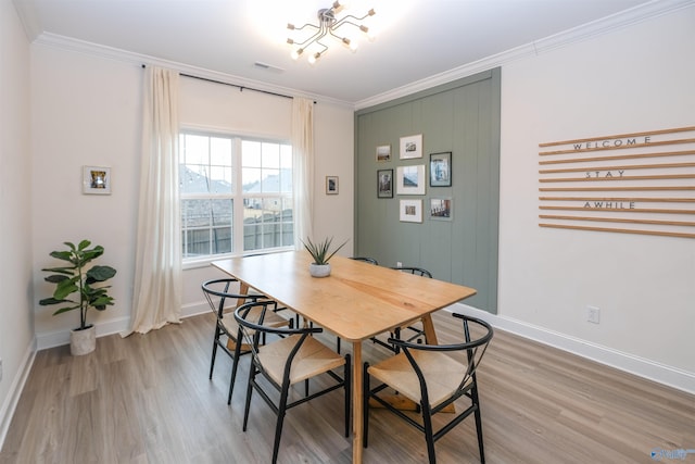 dining area featuring an inviting chandelier, crown molding, and light hardwood / wood-style flooring