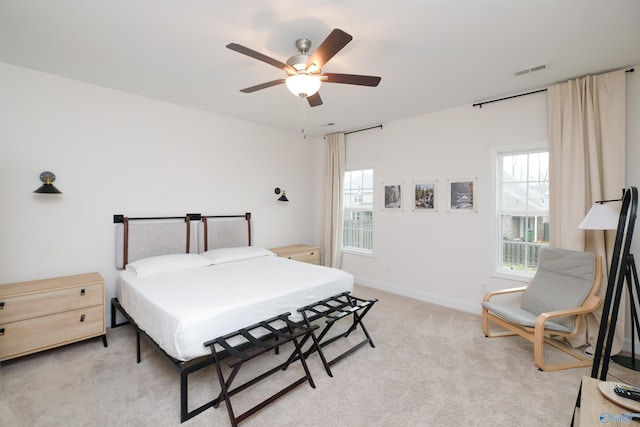 bedroom featuring light carpet, ceiling fan, and multiple windows