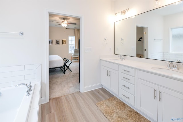 bathroom with ceiling fan, a tub to relax in, hardwood / wood-style floors, and vanity